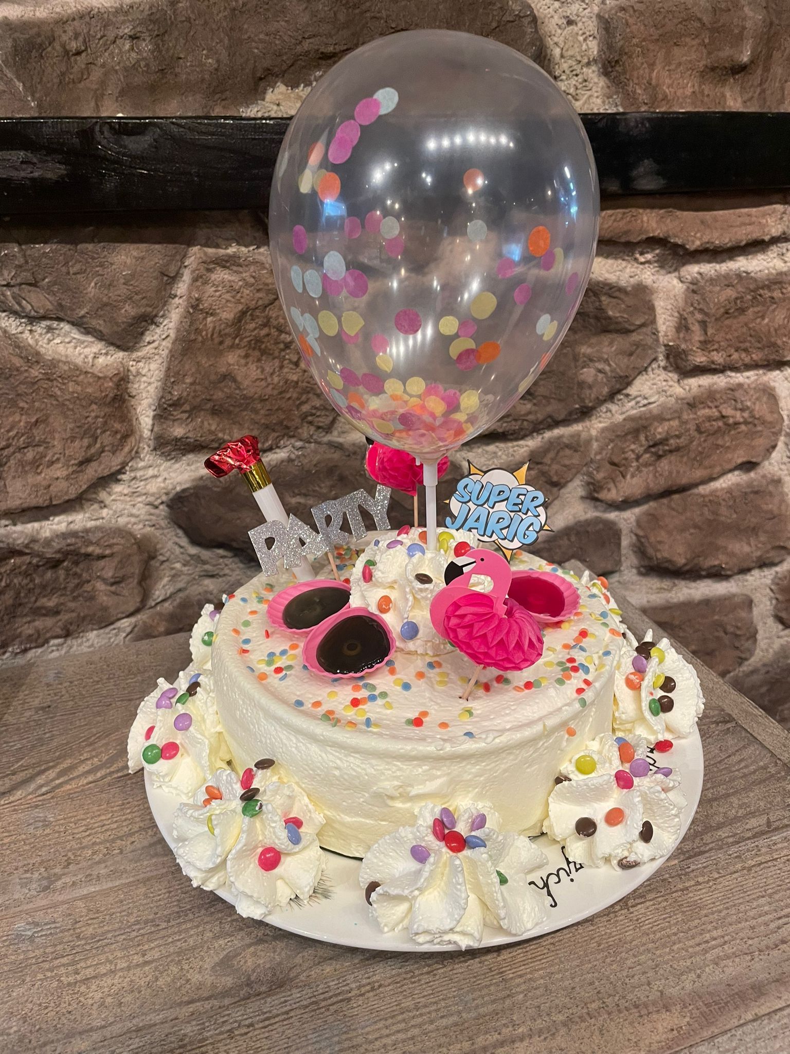 Taart met witte glazuur, hagelslag, roze flamingo-decoratie, ballon en 