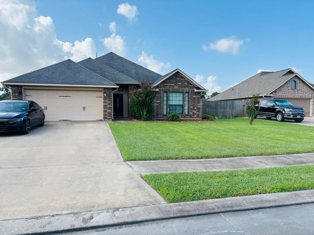 A brick-and-siding house with a beige garage door and a well-manicured lawn.