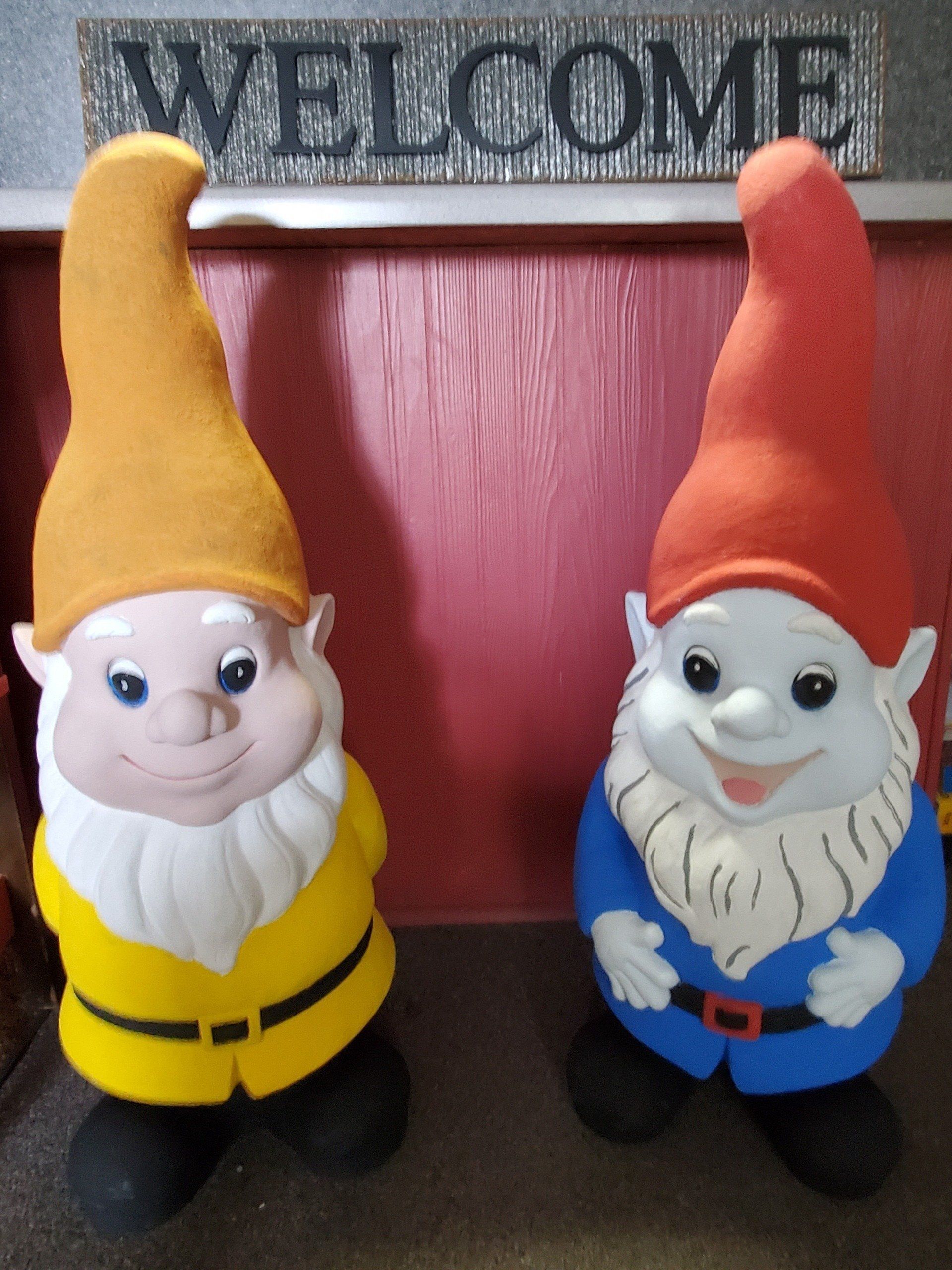 Two gnomes in front of a welcome sign