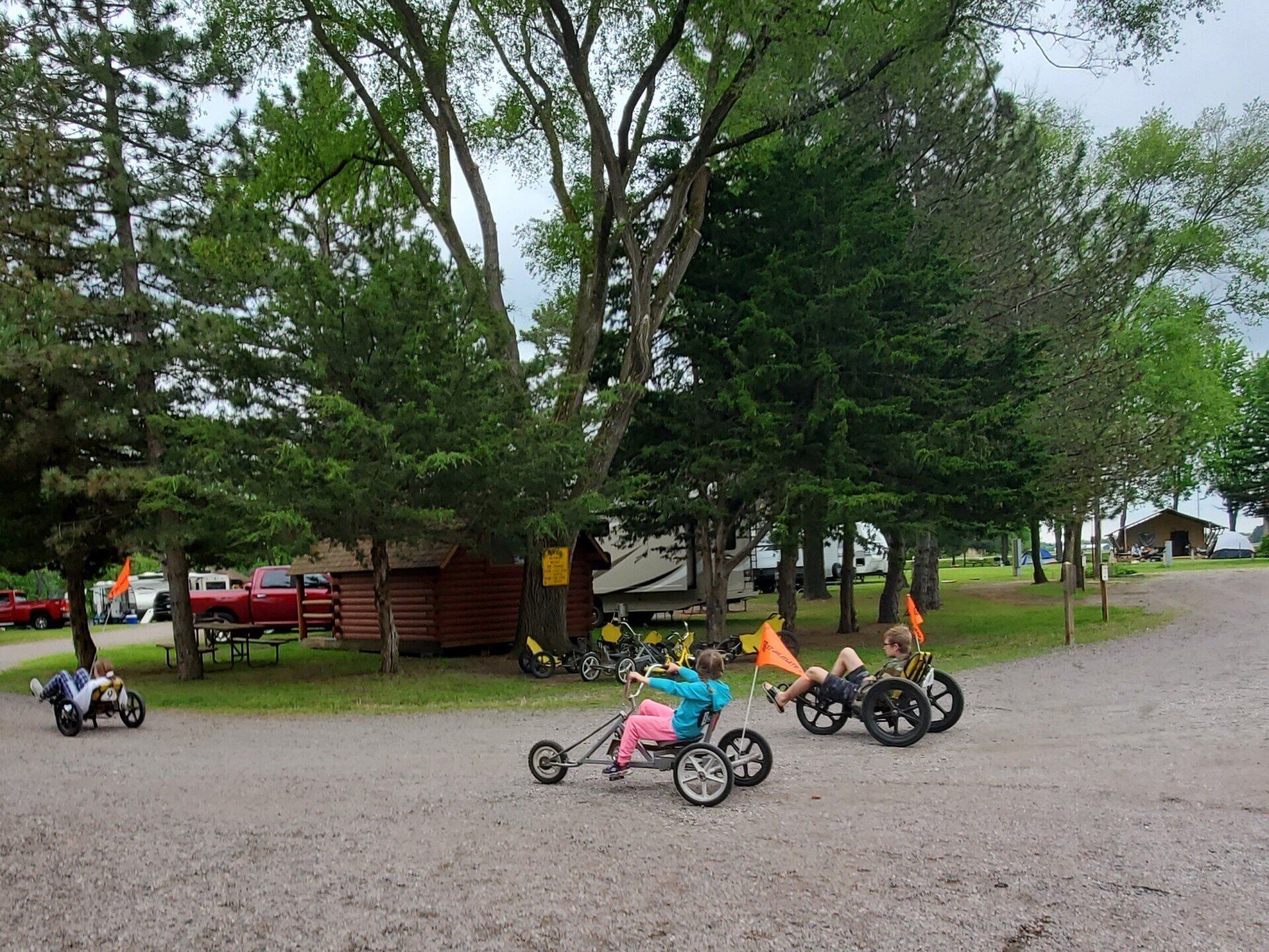 A group of people are riding tricycles on a gravel road.