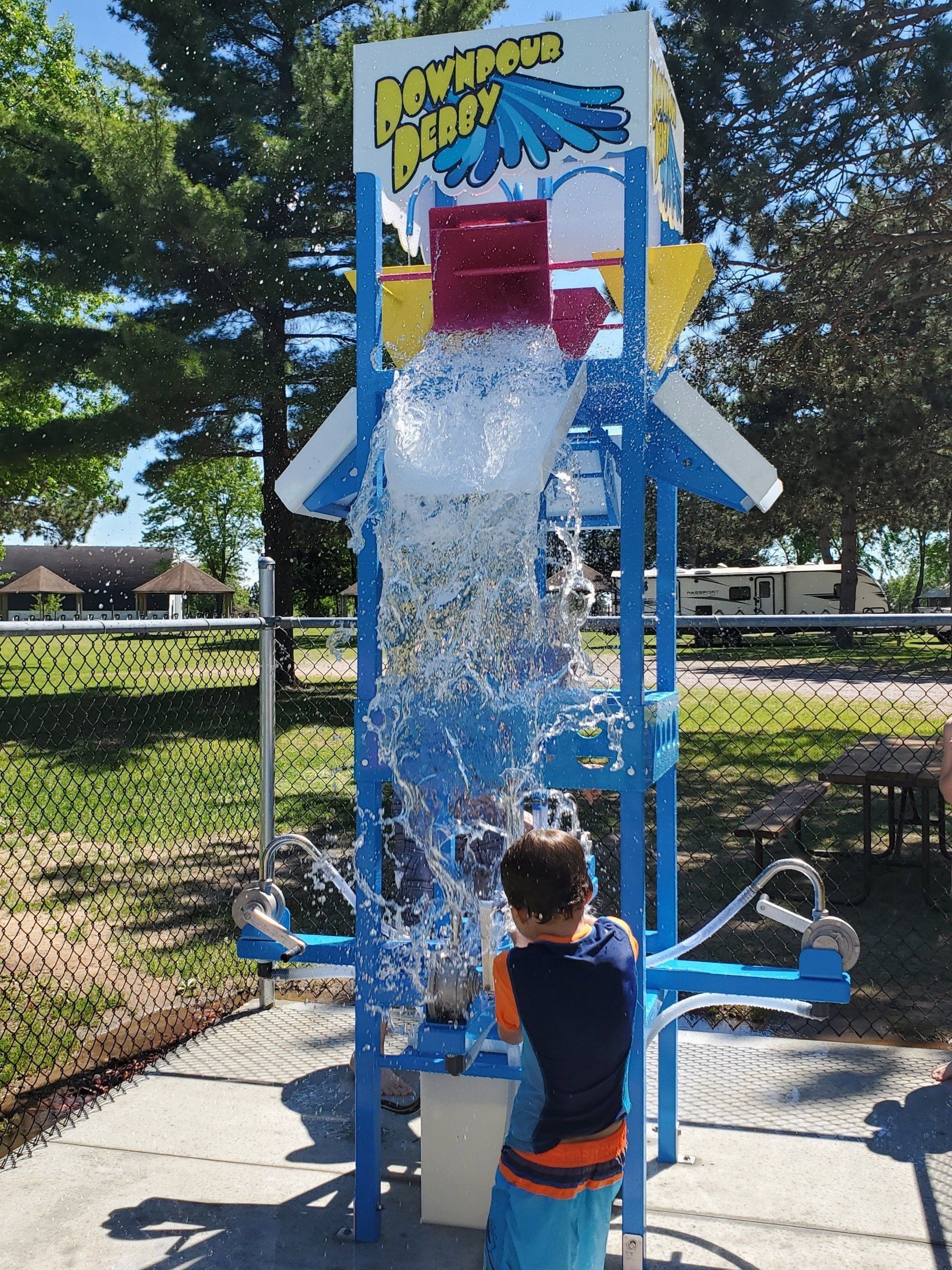 A boy is standing in front of a machine that says newport splash