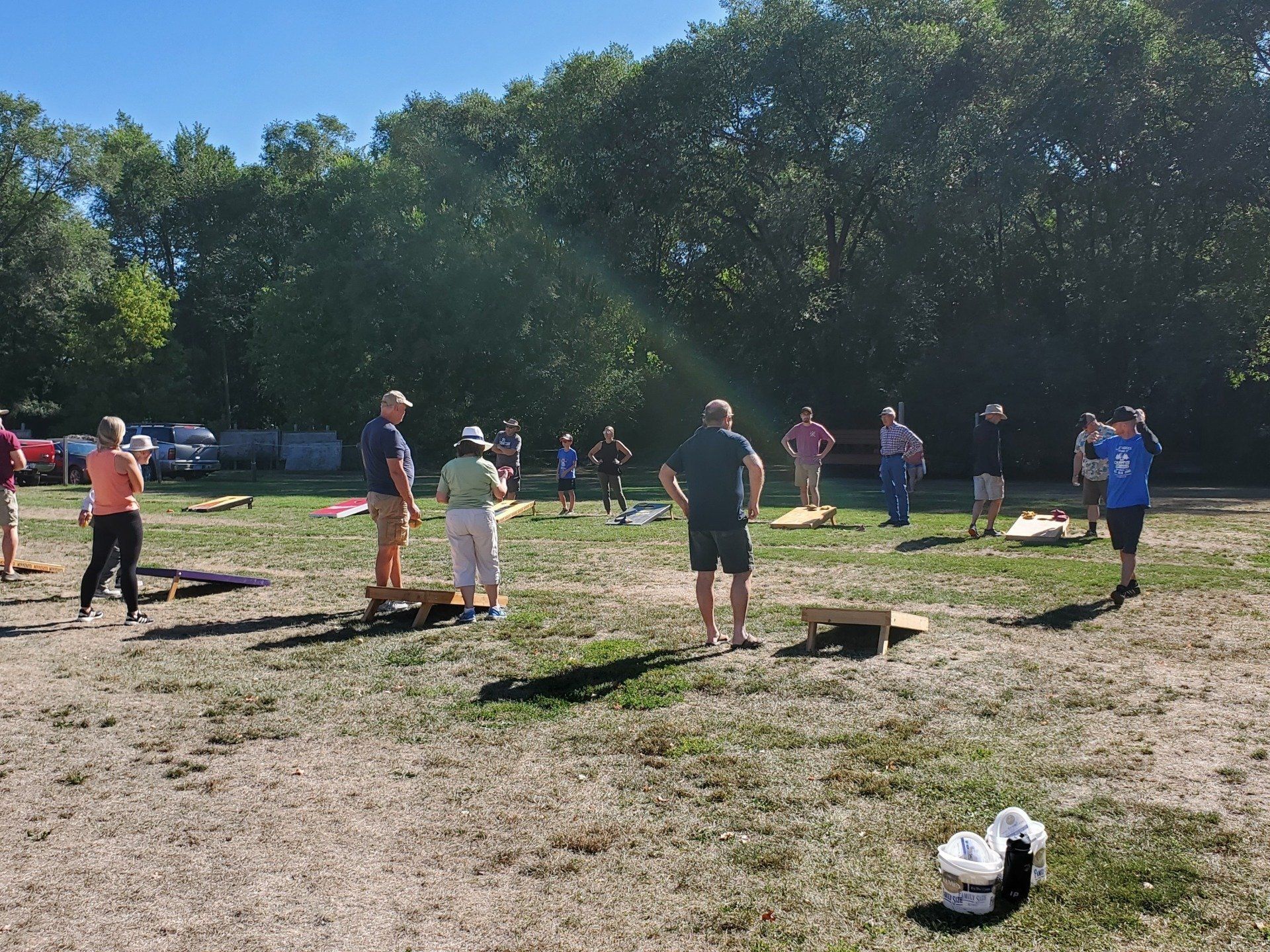 A group of people are playing cornhole in a field