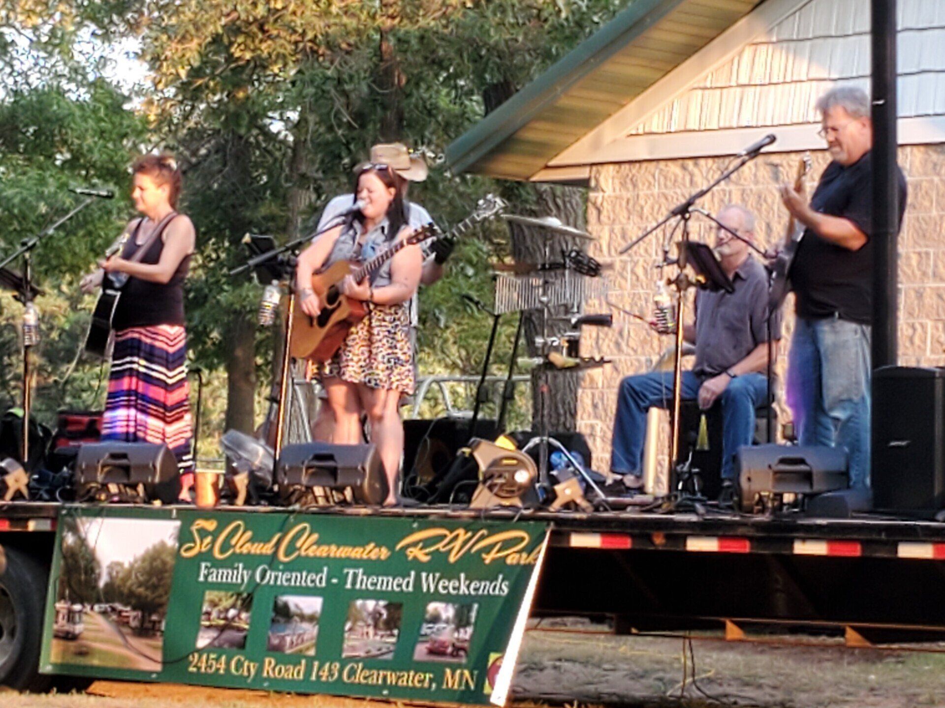 A group of people playing instruments on a stage in front of a sign that says st cloud community rv park