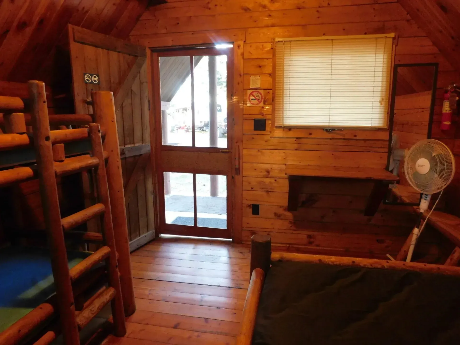 A wooden cabin with bunk beds and a fan