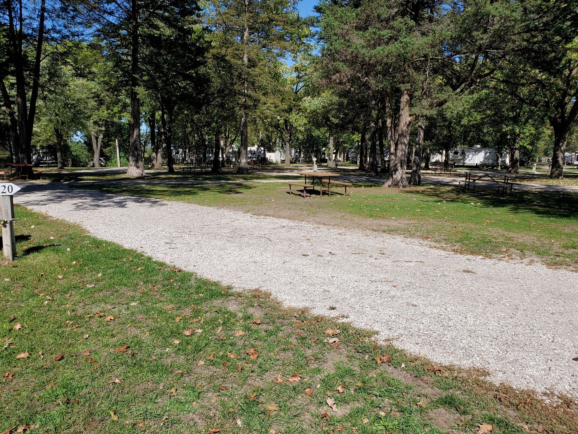A gravel road going through a park surrounded by trees and grass.