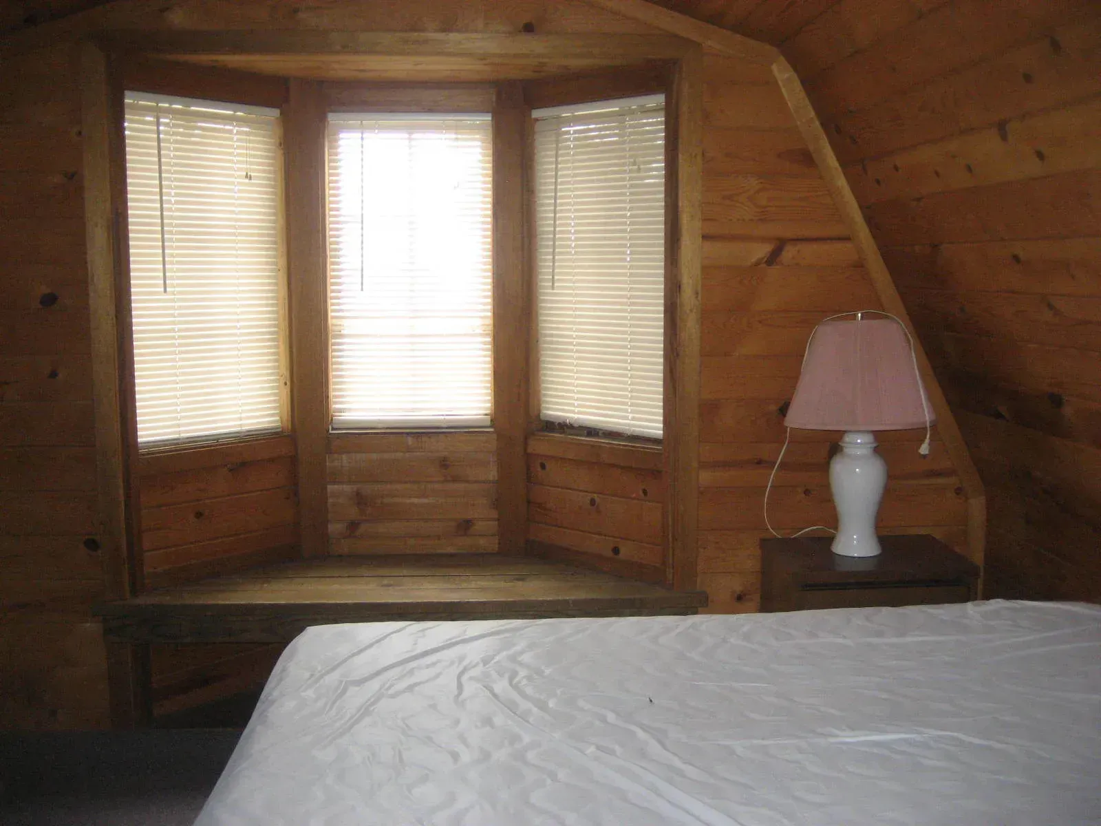 A bedroom with a bed a lamp and a window