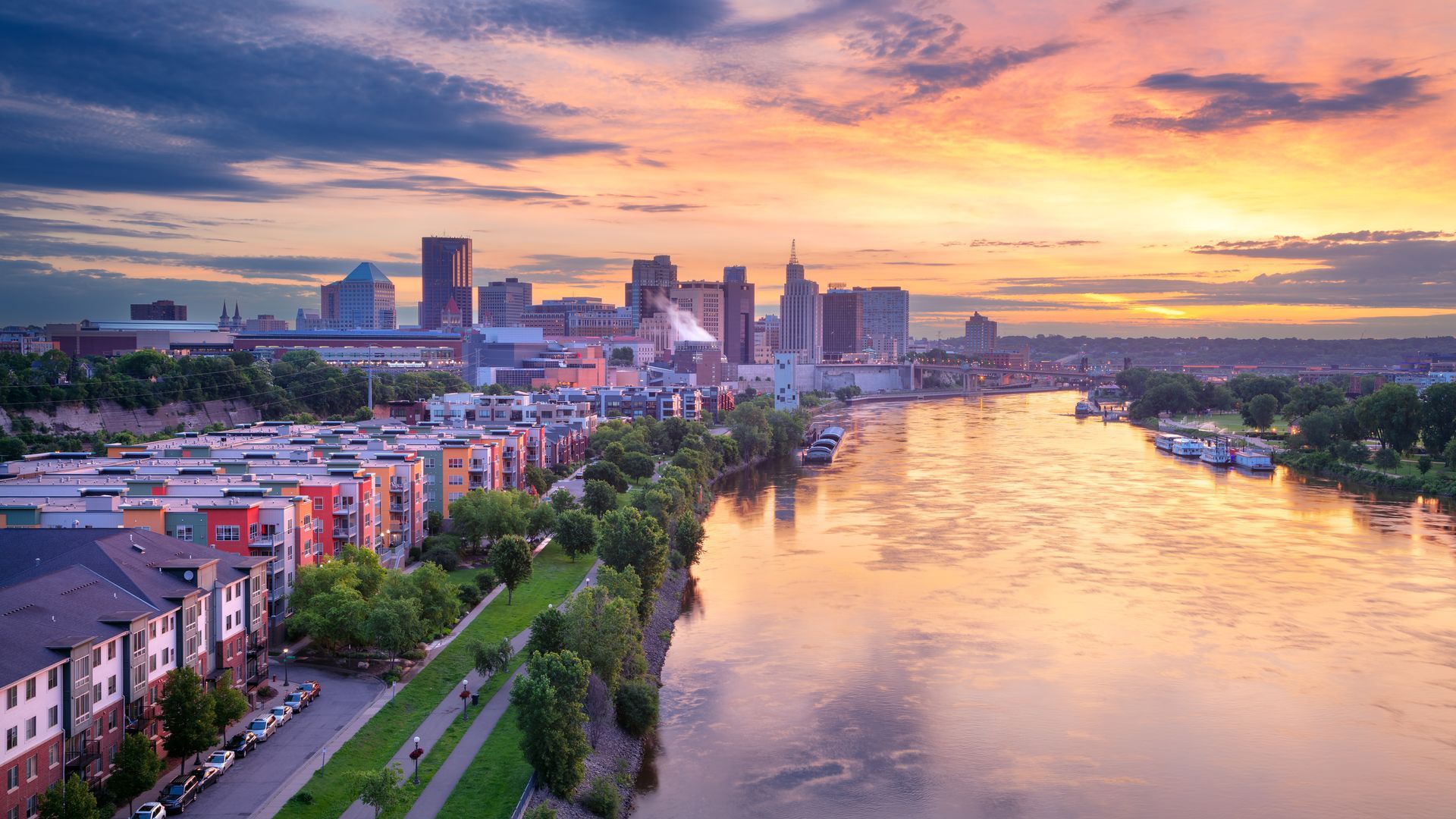 An aerial view of a city skyline over a river at sunset.
