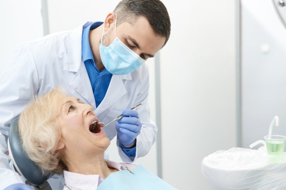 Dentist With Patient Installing Dentures — The Denture Care Group Sunshine Coast in Caloundra, QLD