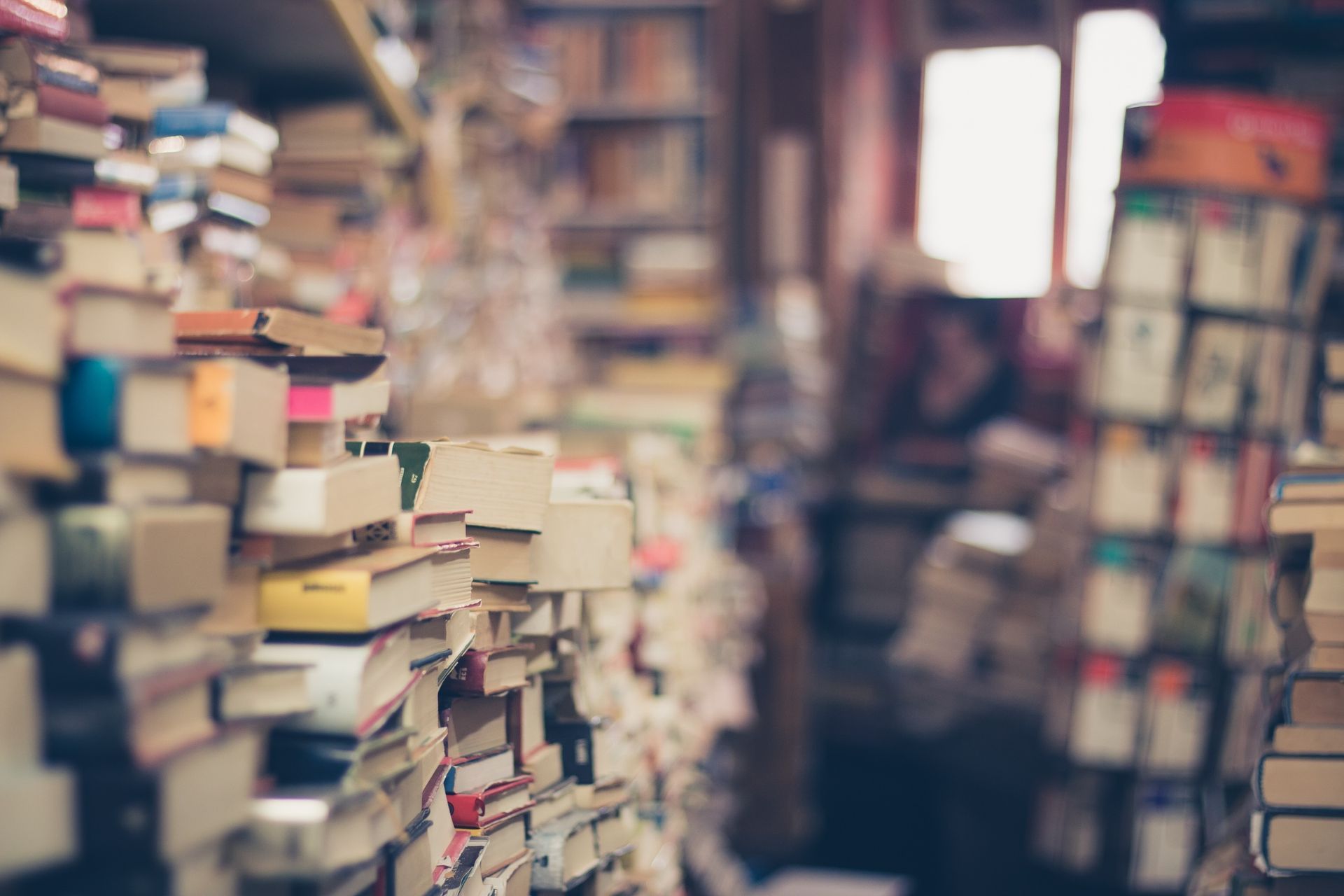 In einer Bibliothek sind viele Bücher übereinander gestapelt.