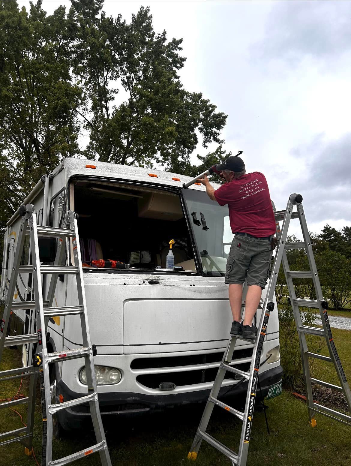 A man is standing on a ladder working on a rv.