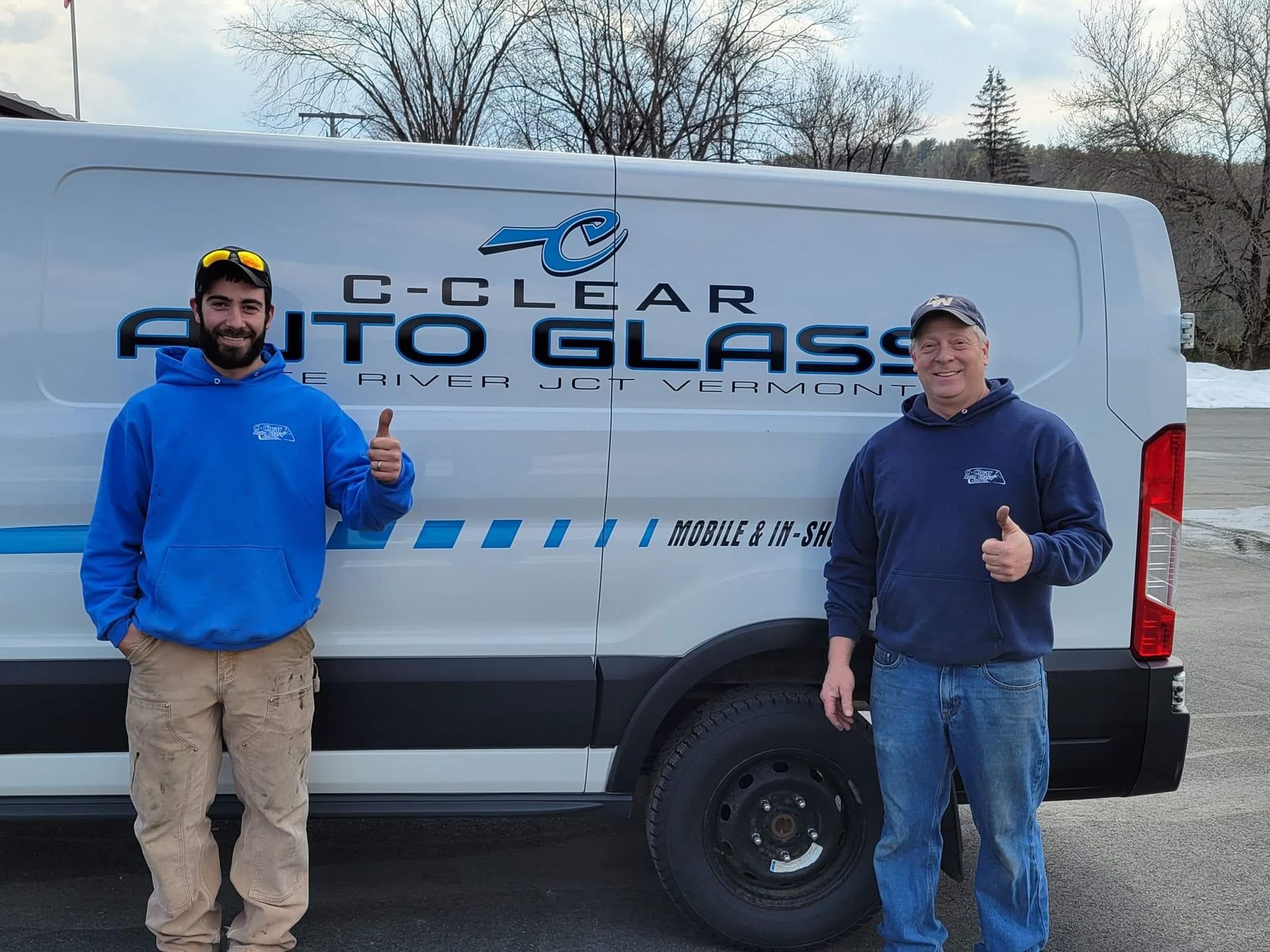 Two men are standing in front of a c-clear auto glass van.
