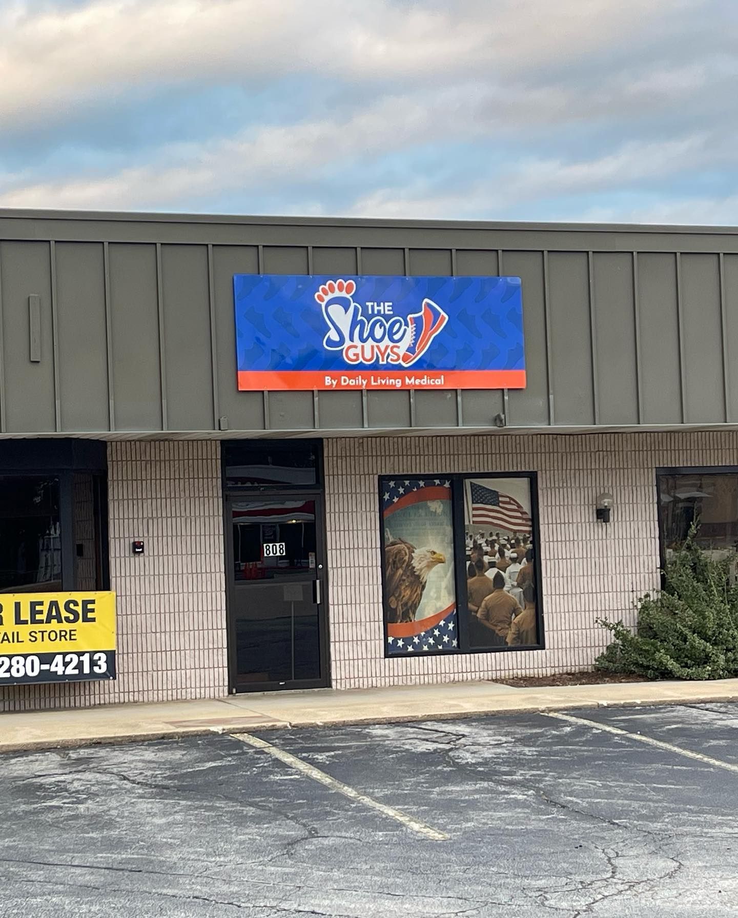 Storefront with blue and orange sign reading “The Dog House” above a door and windows on a strip mall.