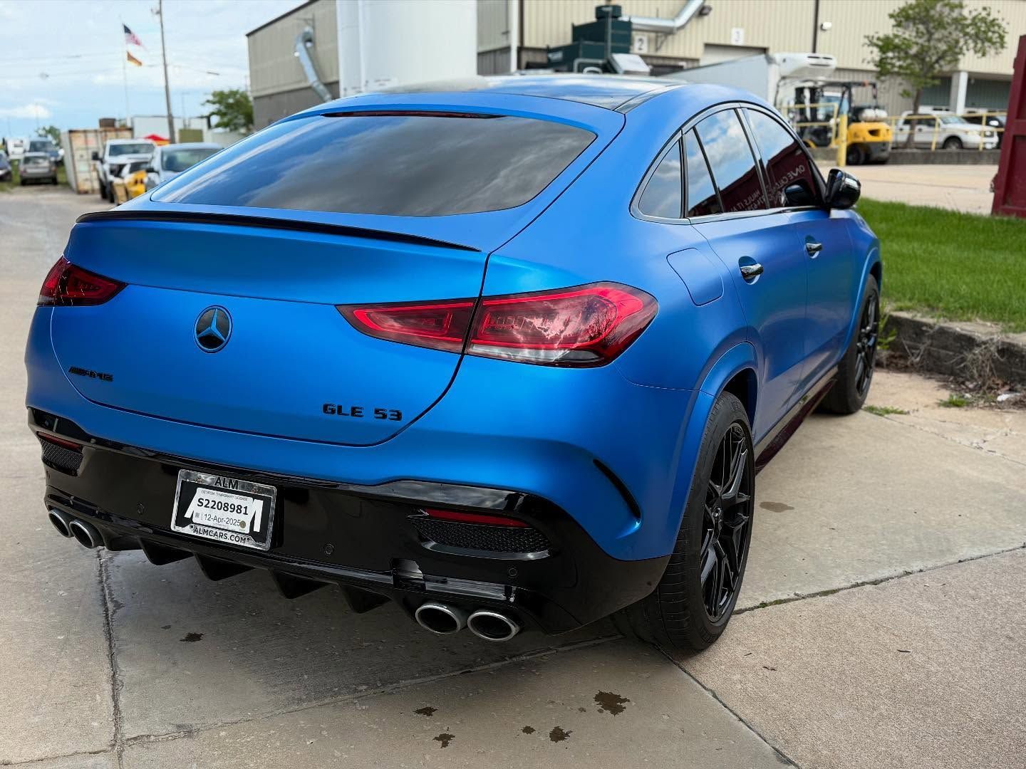 Blue SUV parked on a sidewalk near a building, rear three-quarter view
