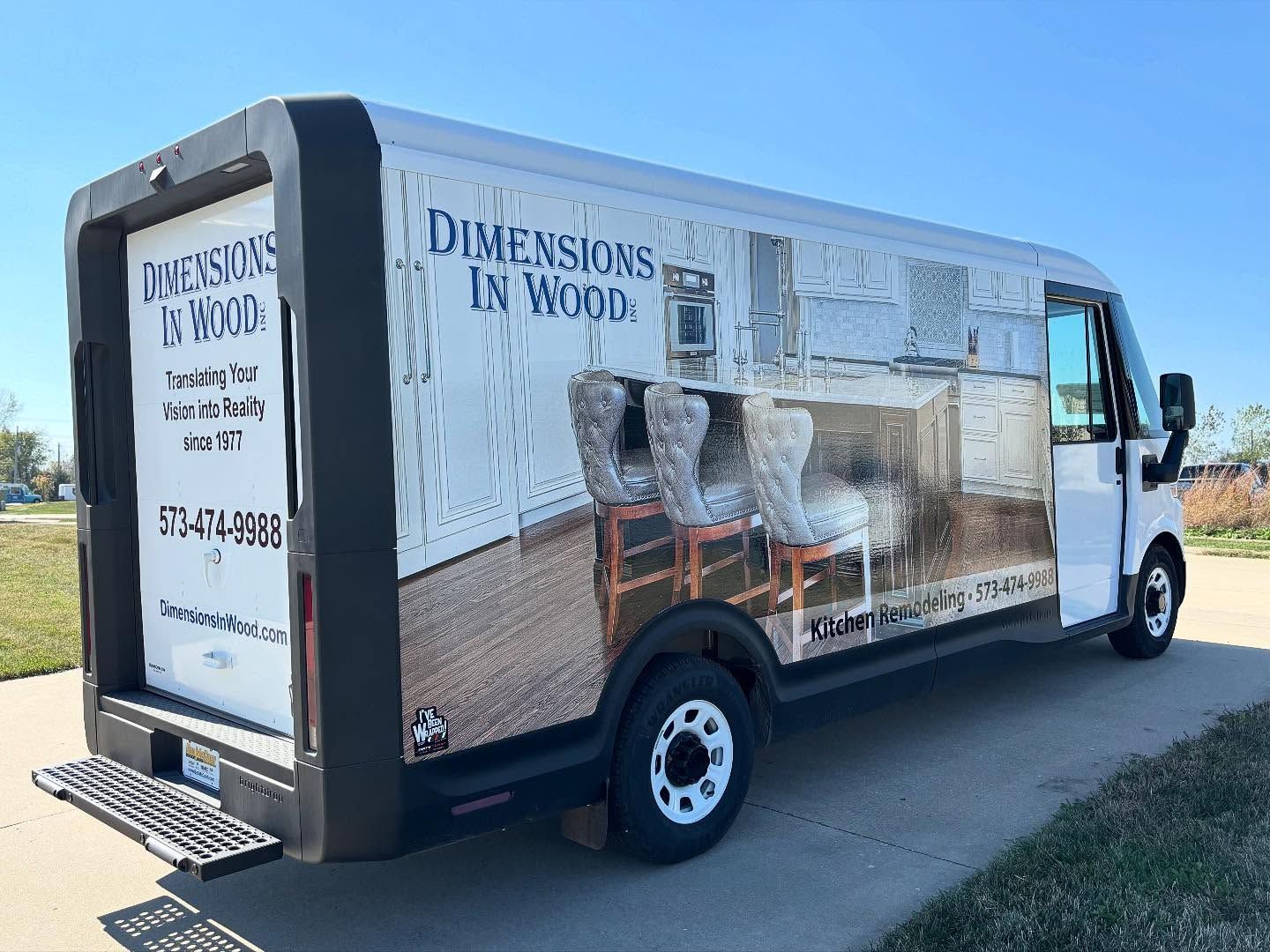 White box truck with “Dimensions in Wood” graphics parked on a sunny roadside