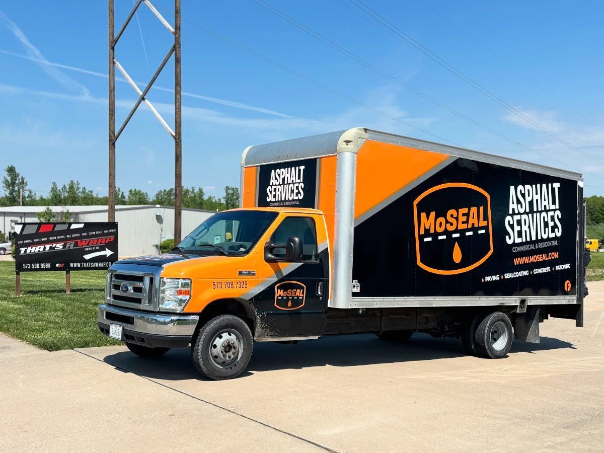 Orange and black Mo'Real Asphalt Services truck parked on a sunny roadside
