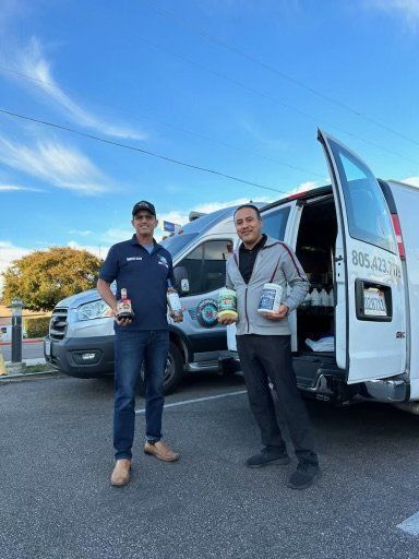 Two men are standing next to a van in a parking lot.