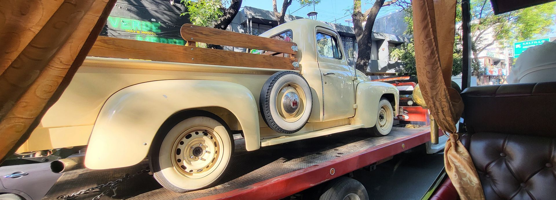 Vintage cream convertible on a display platform in an indoor exhibit, with a spare tire mounted on the side.