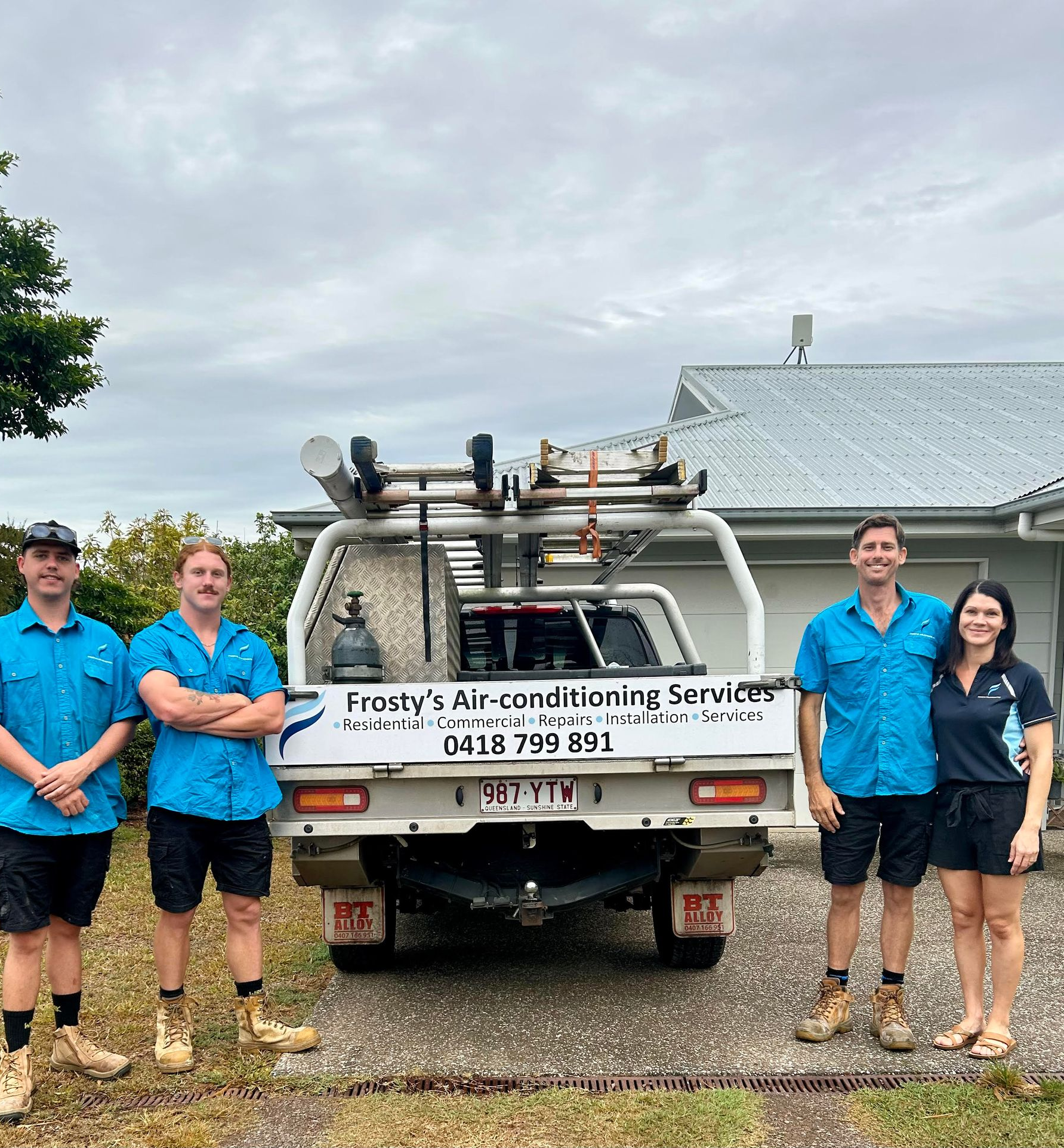 Four People in Blue Shirts Stand Next to a White Truck With — FrostyCo Air-Conditioning in Cannonvale, QLD