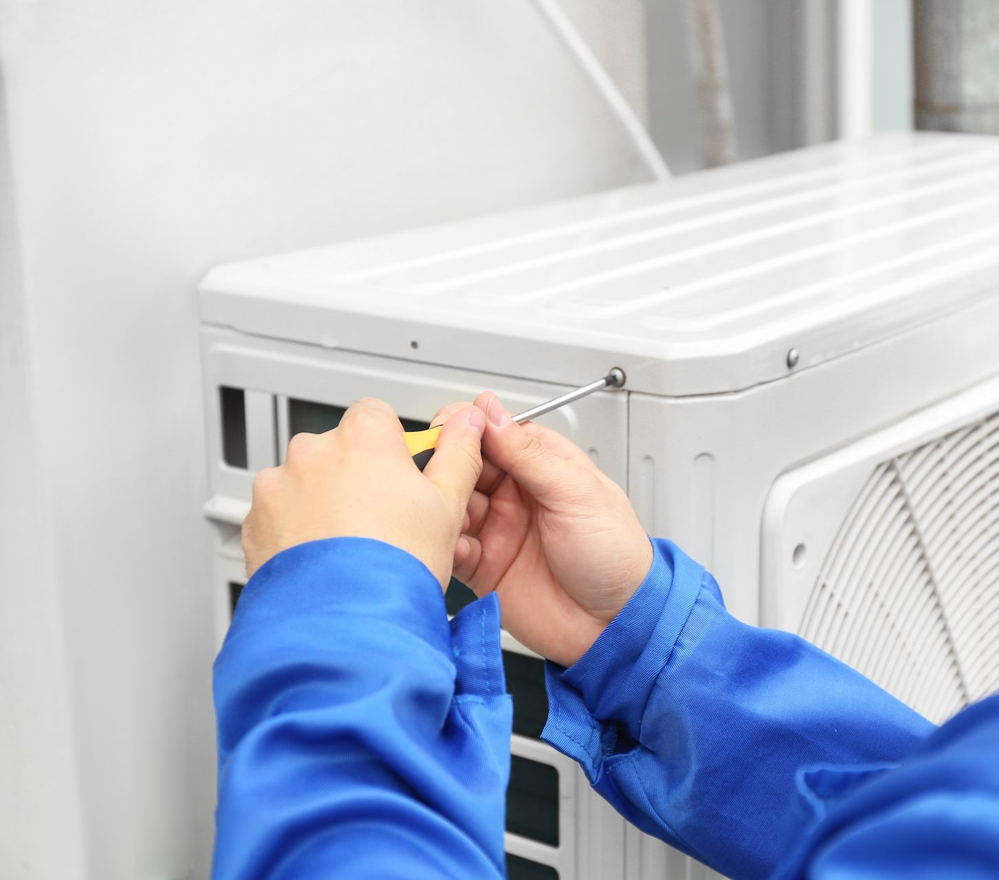 Person Servicing Wall-Mounted Air Conditioner Indoors — FrostyCo Air-Conditioning in Cannonvale, QLD