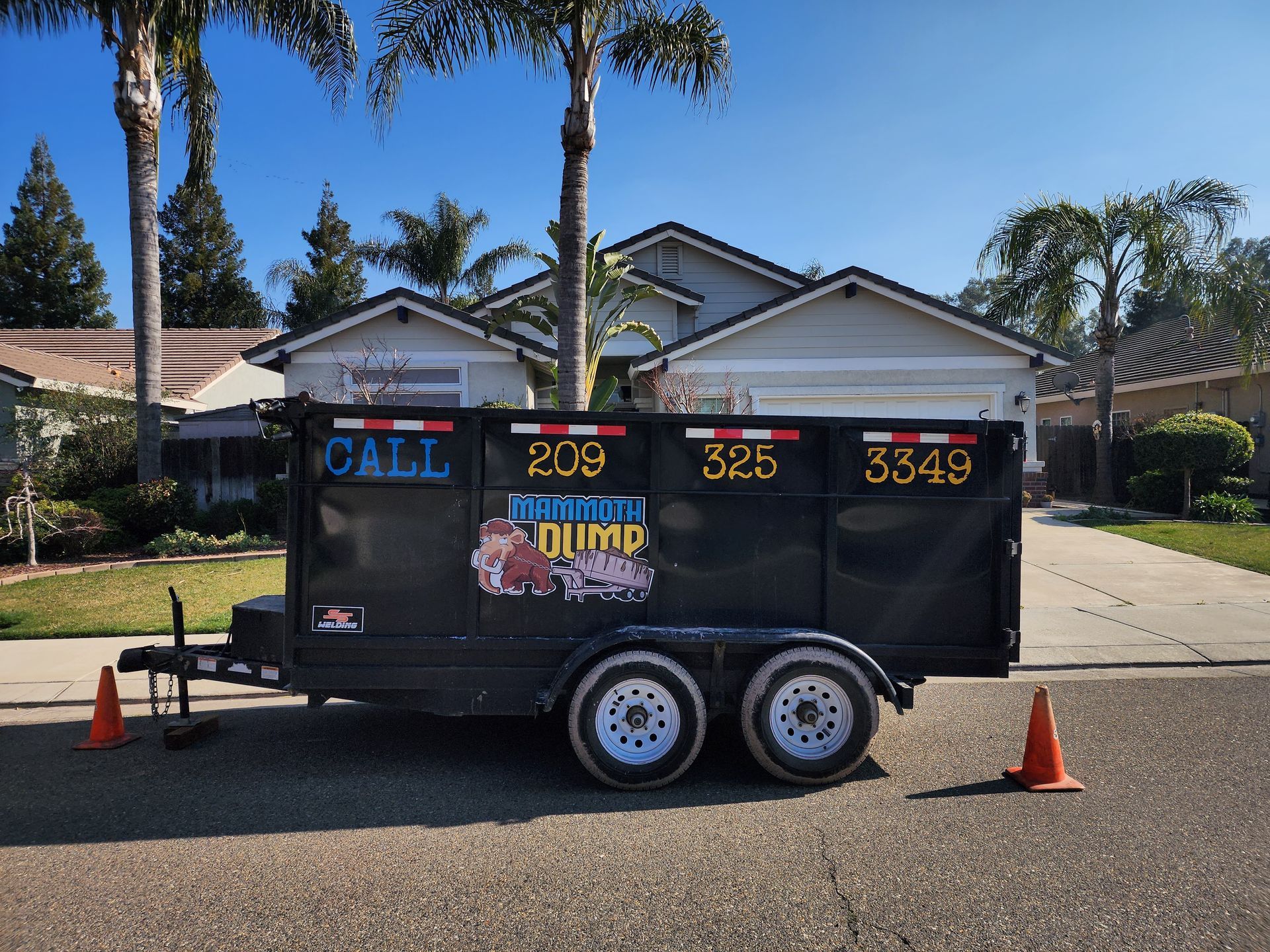 A dump trailer is parked in front of a house