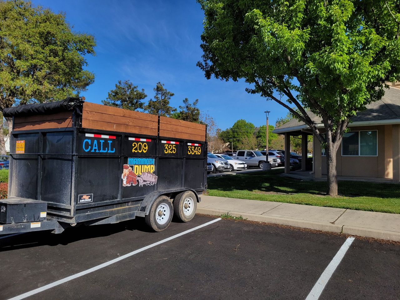 A dumpster is parked in a parking lot in front of a building.