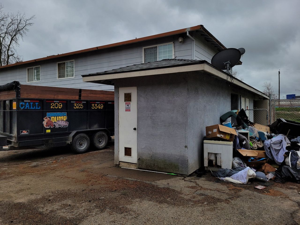 A dumpster is parked in front of a house.