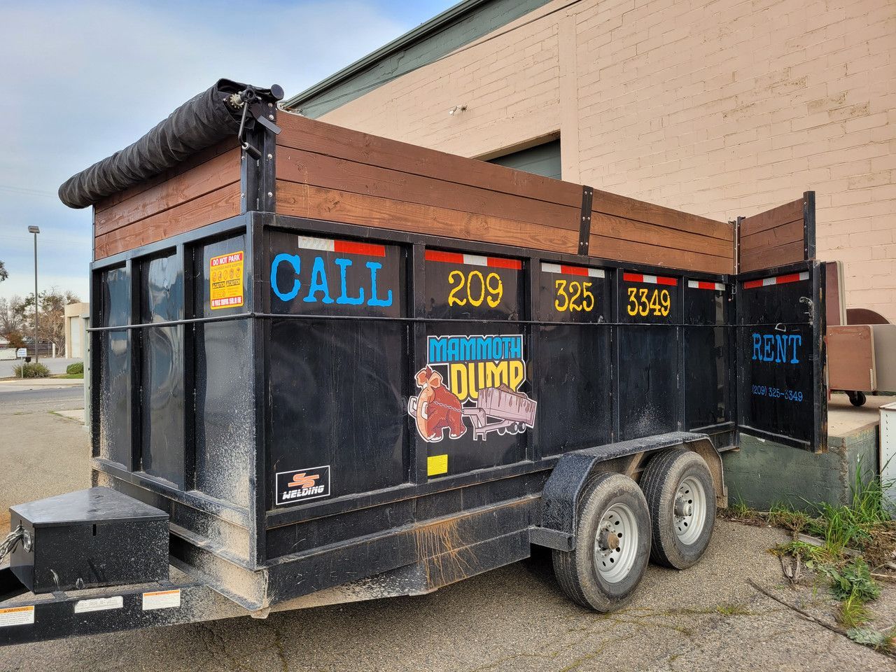 A dumpster trailer is parked in front of a building.