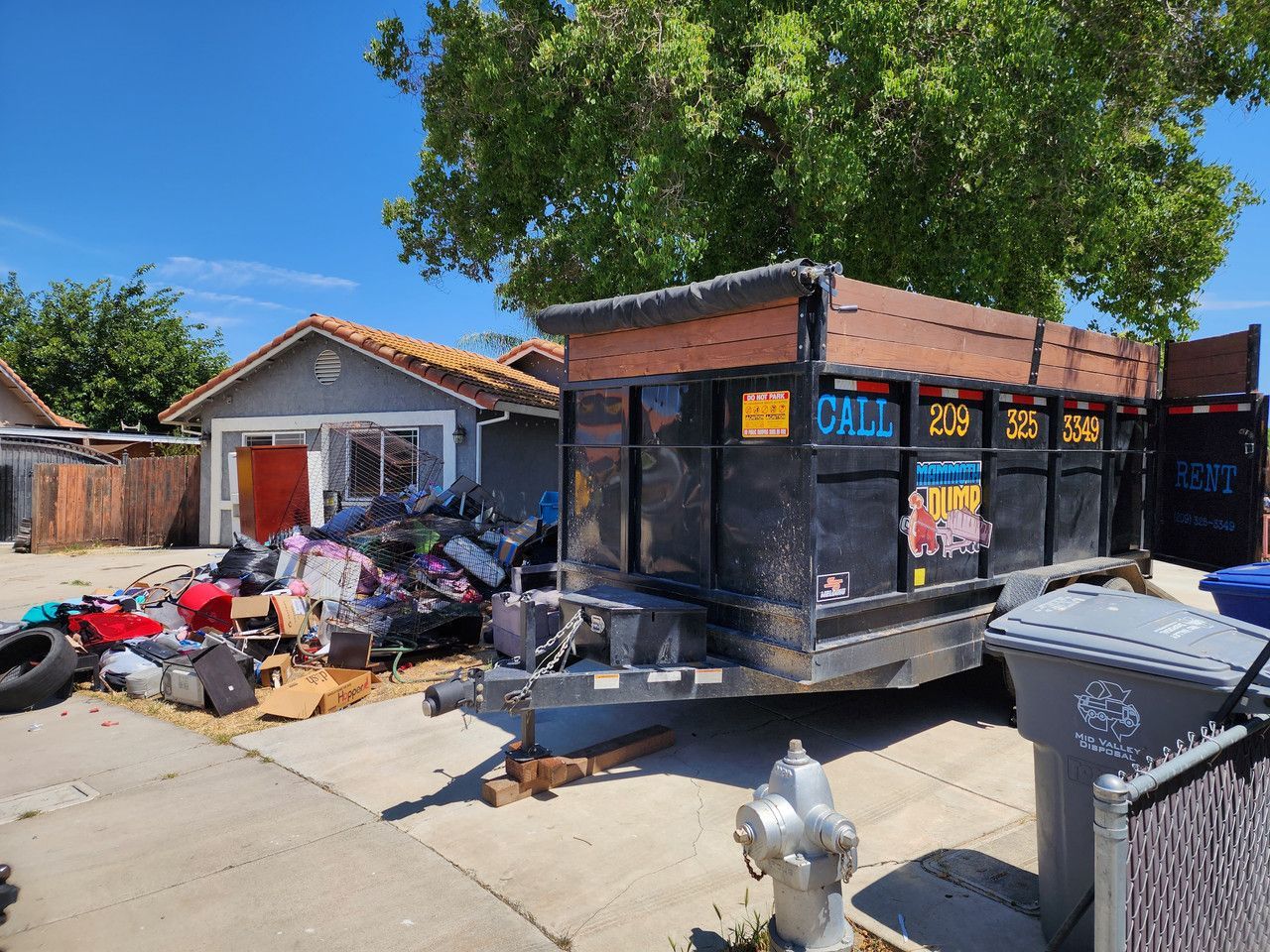 A dumpster is full of trash in front of a house.