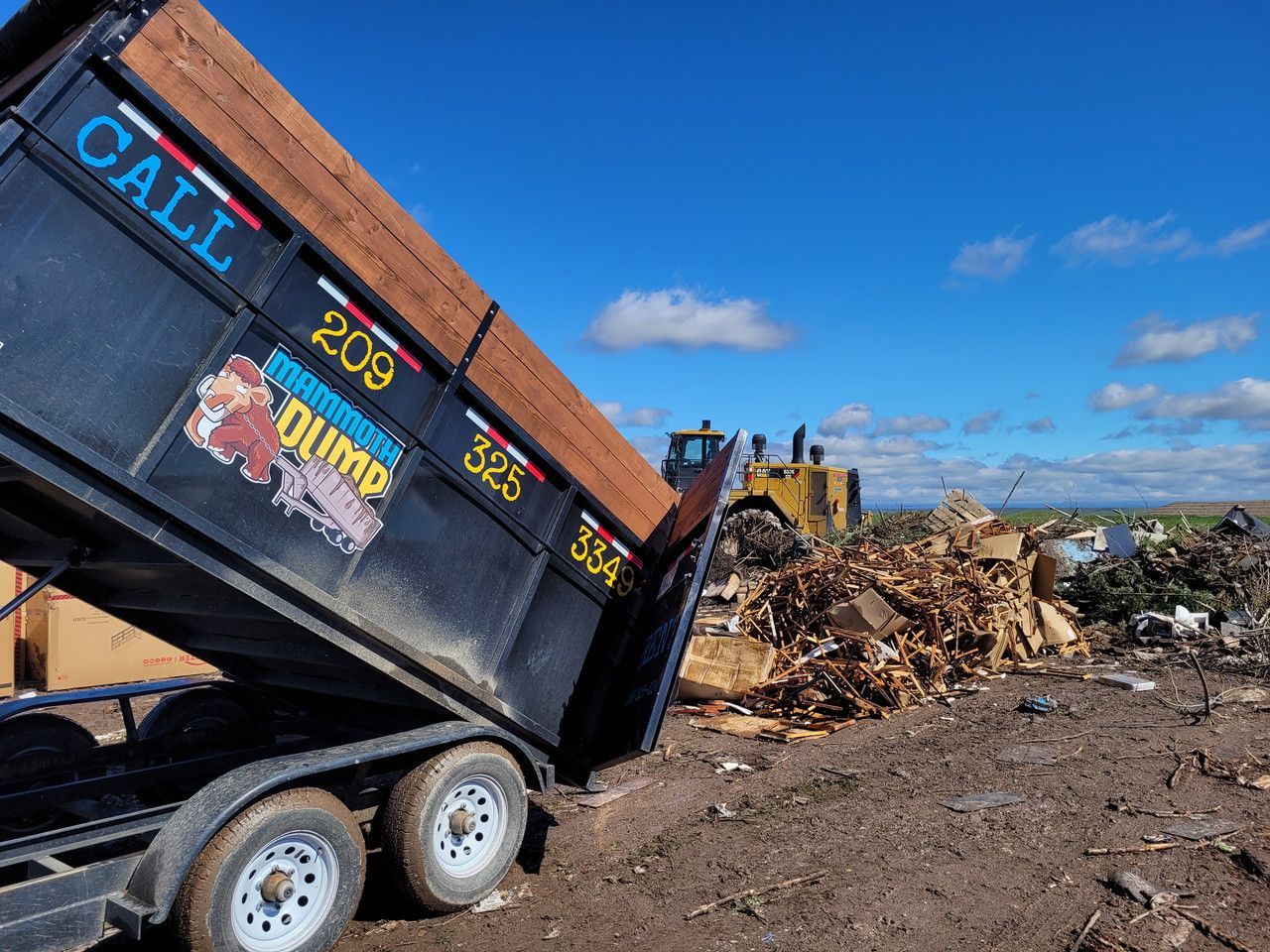 A dumpster is being dumped into a pile of trash.