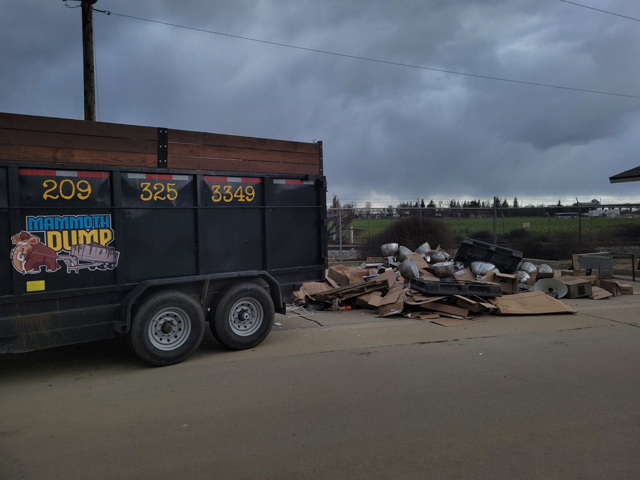 A dump truck is parked next to a pile of trash.
