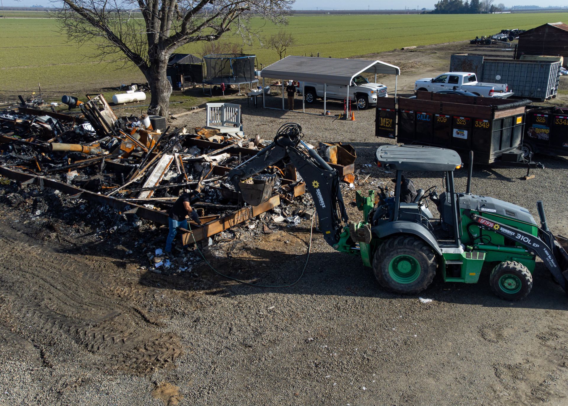 a backhoe being used to clean out a large pile of burnt debris