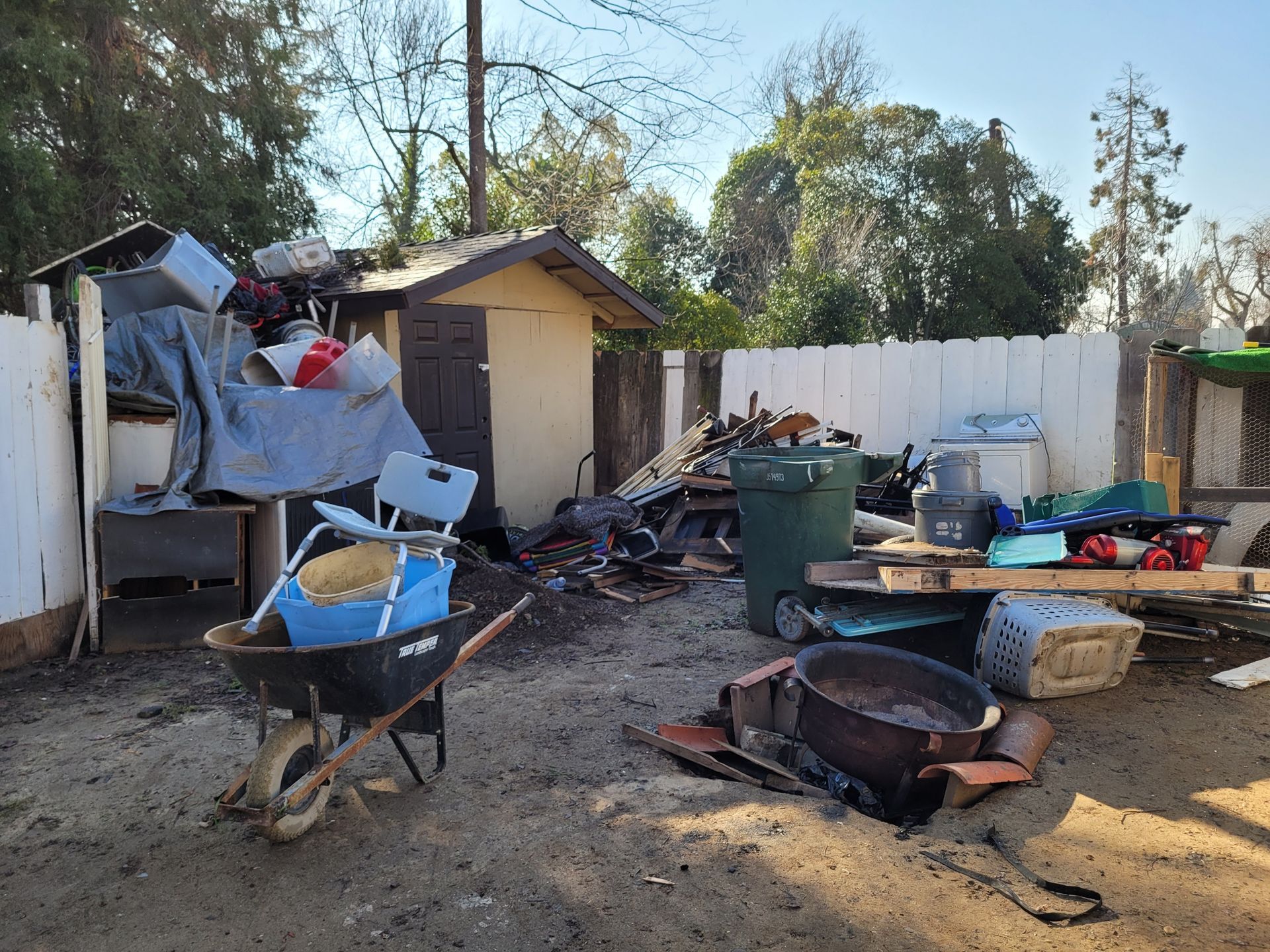 A wheelbarrow is filled with trash in a backyard.