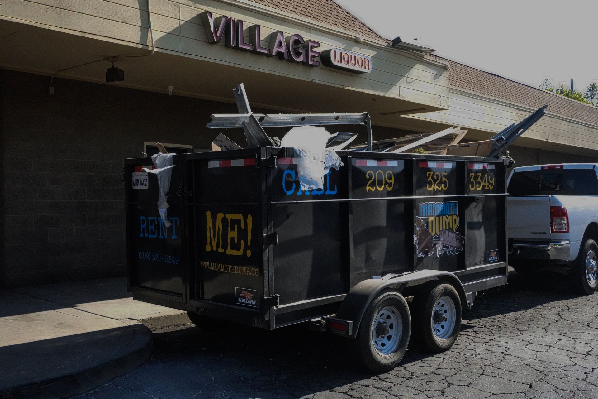 A dumpster is parked in front of a building that says village