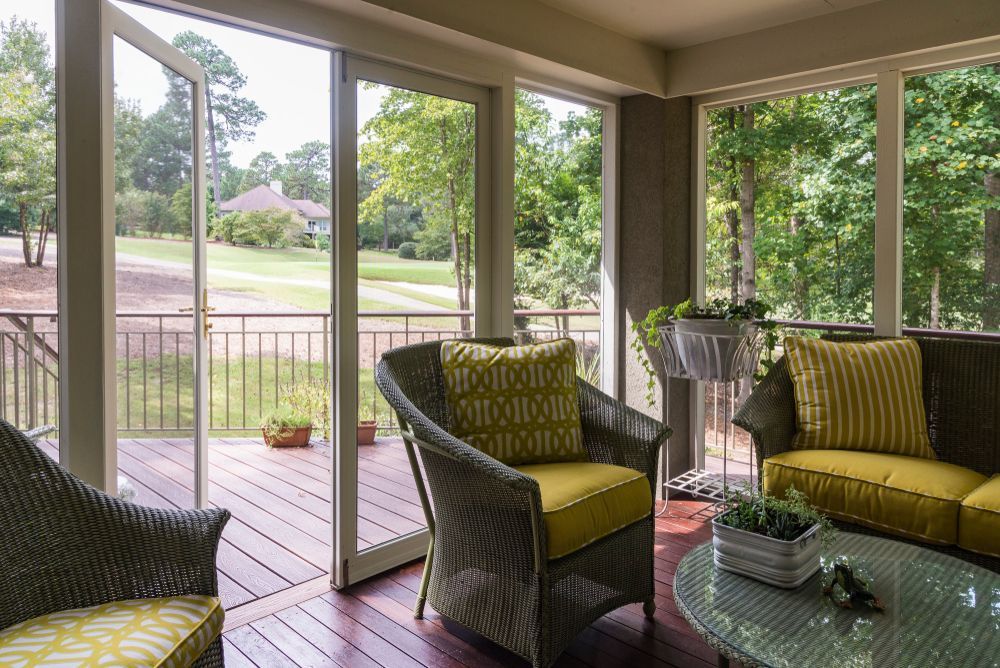 A screened in porch with a couch , chairs , and a table.