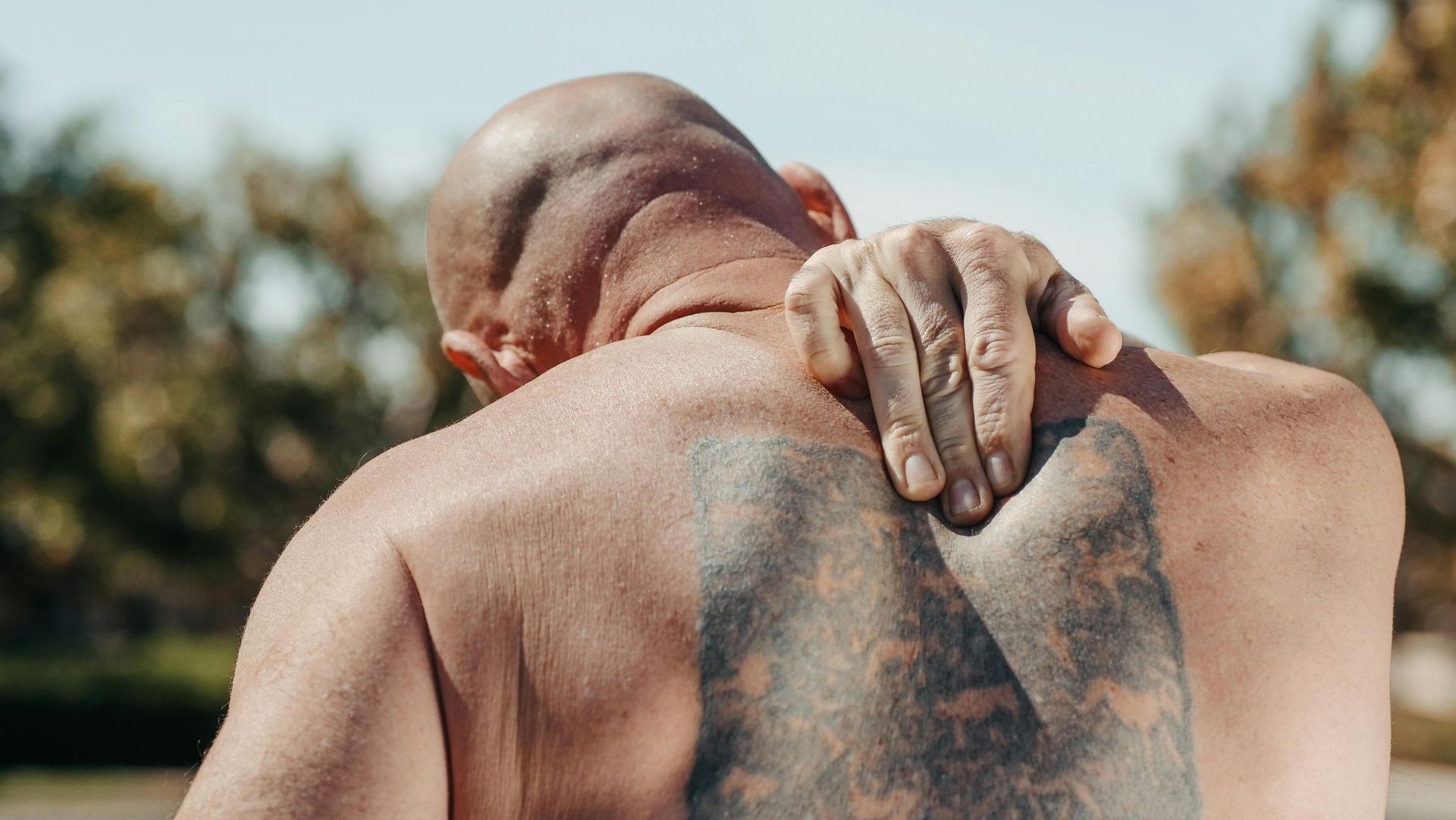 Bald Person Holding Their Right Shoulder — Spinal Decompression Sunshine Coast In Maroochydore, QLD