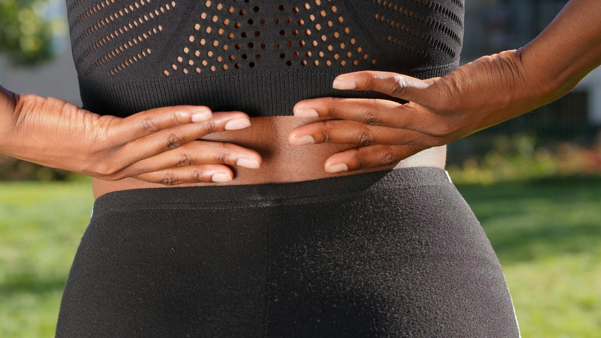 Woman's Hands Supporting Lower Back — Spinal Decompression Sunshine Coast In Mooloolaba, QLD