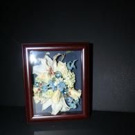 Framed floral artwork with blue and white flowers on a dark wall