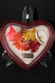 Heart-shaped red-framed decorative keepsake with orange and yellow flowers on a black stand