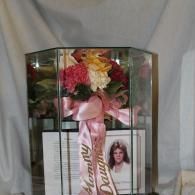 Bouquet of pink, yellow, and white flowers in a glass vase with a pink ribbon and card