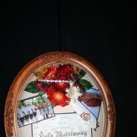 Oval framed floral arrangement on a white memorial plaque against a dark background