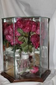 Pink roses in a glass display case on a wooden base