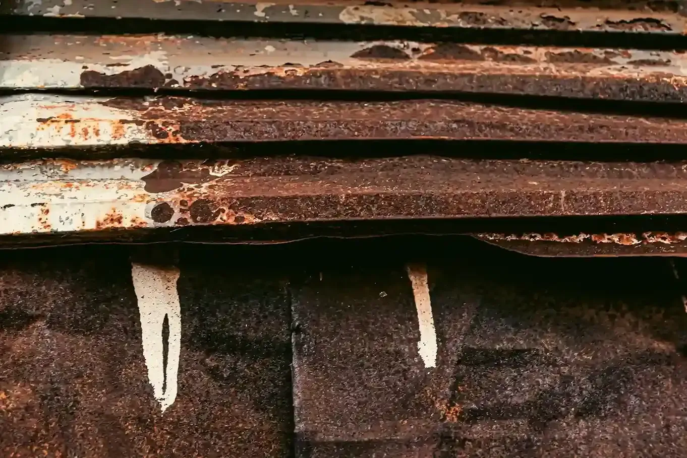 Rusty metal panels with peeling white paint, and white streaks.