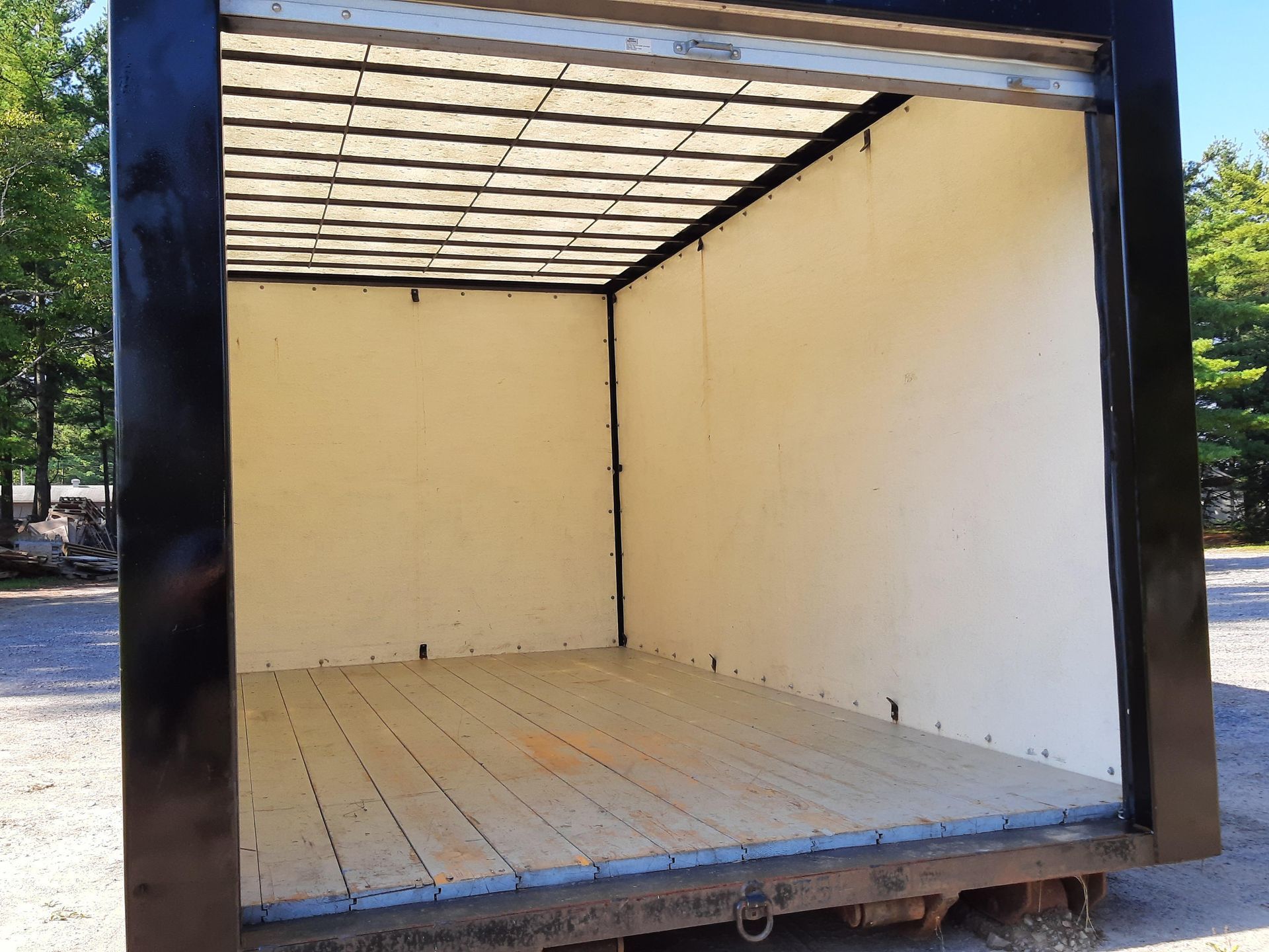 Remorque cargo vide, intérieur beige et châssis noir, vue de l'arrière ouvert.