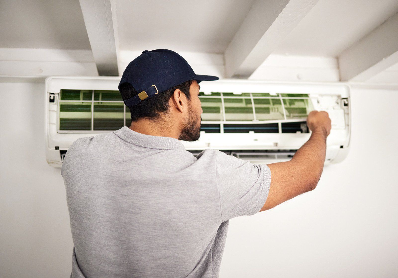 A man is cleaning the filter of an air conditioner.