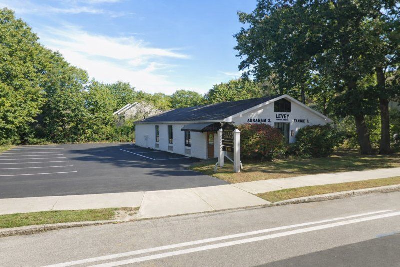 White funeral chapel with paved parking and surrounding trees, supporting families seeking Biddeford, ME cremation services