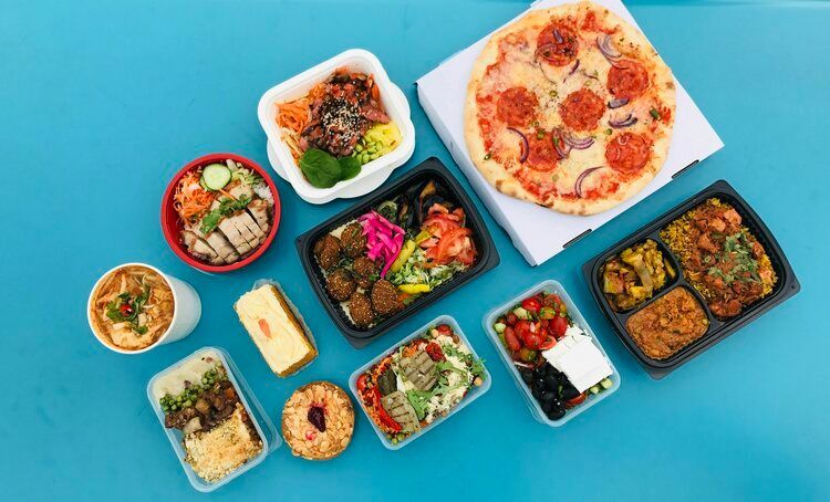 There are many different types of food in plastic containers on a blue table.