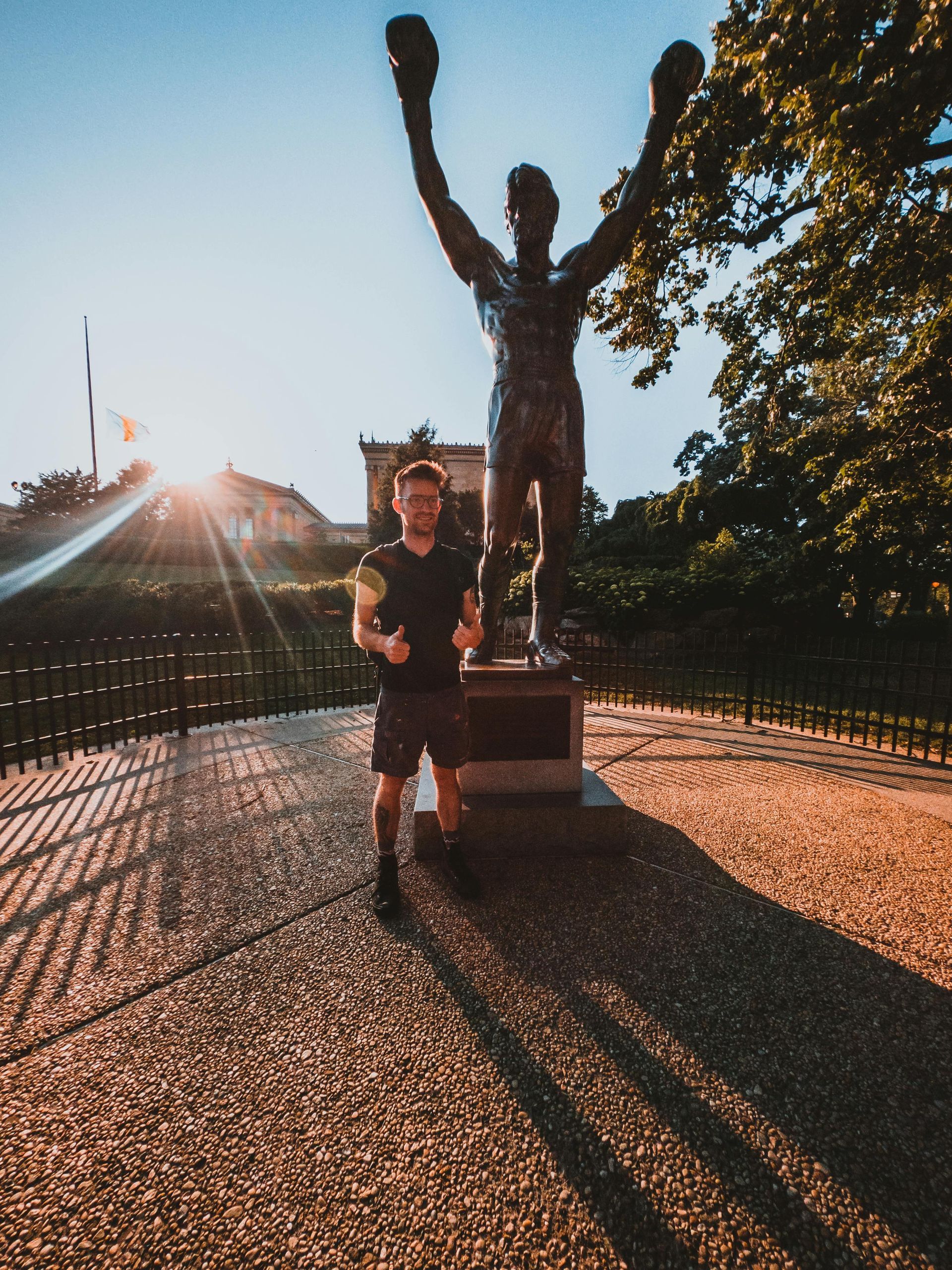 A man is running in front of a statue of rocky balboa