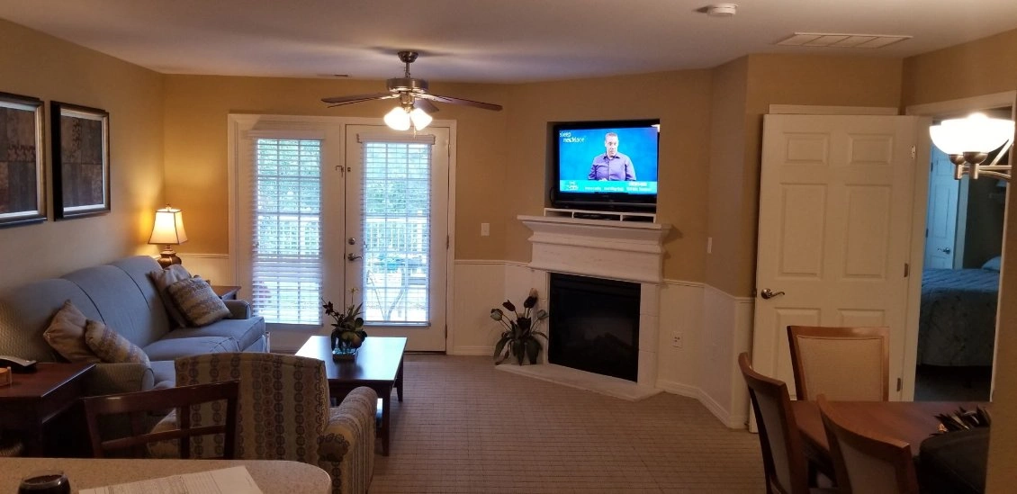 Cozy living room with sofa, fireplace, wall-mounted TV, and French doors