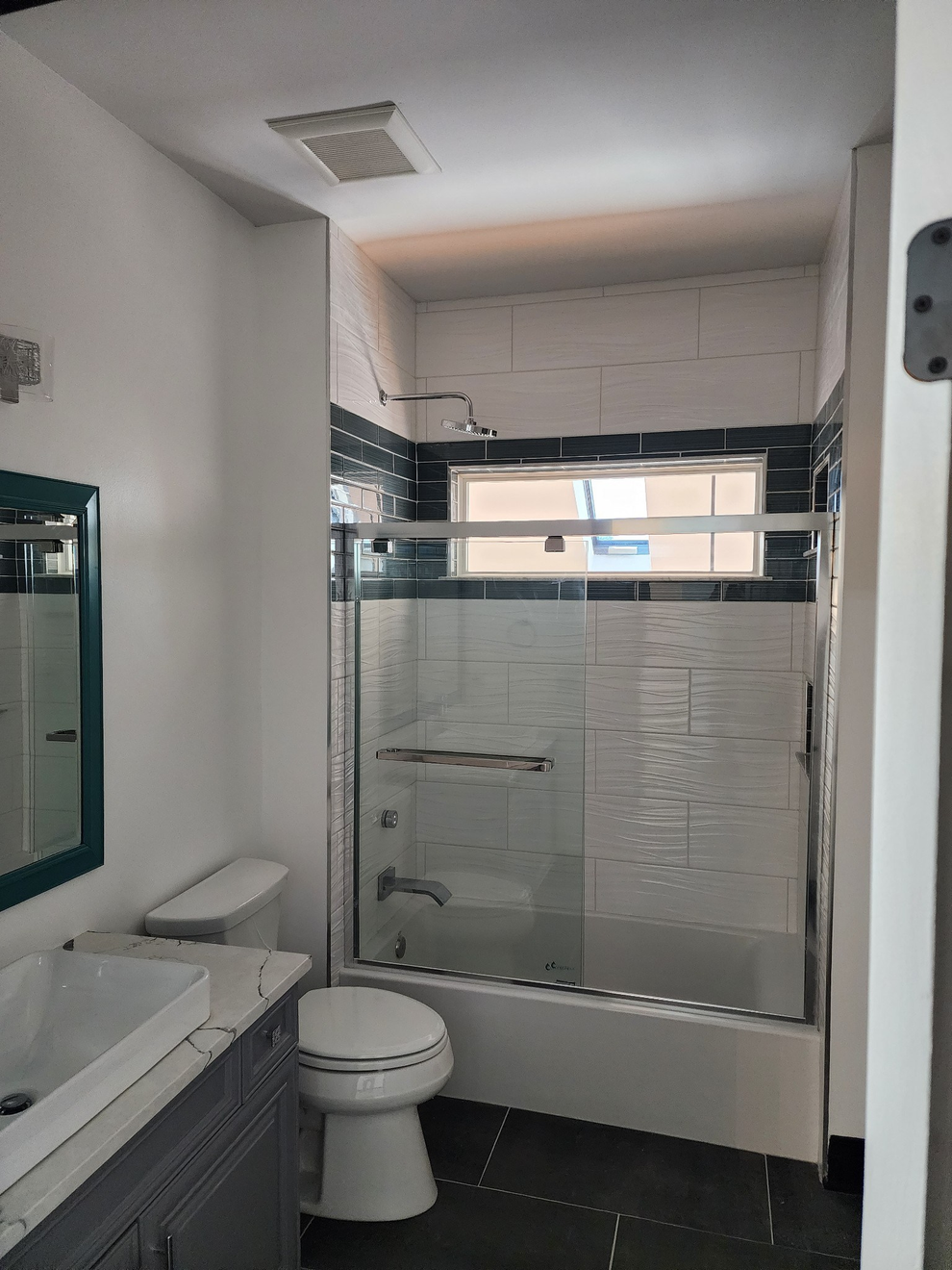 Small bathroom with a toilet, sink, mirror, and glass shower enclosure.
