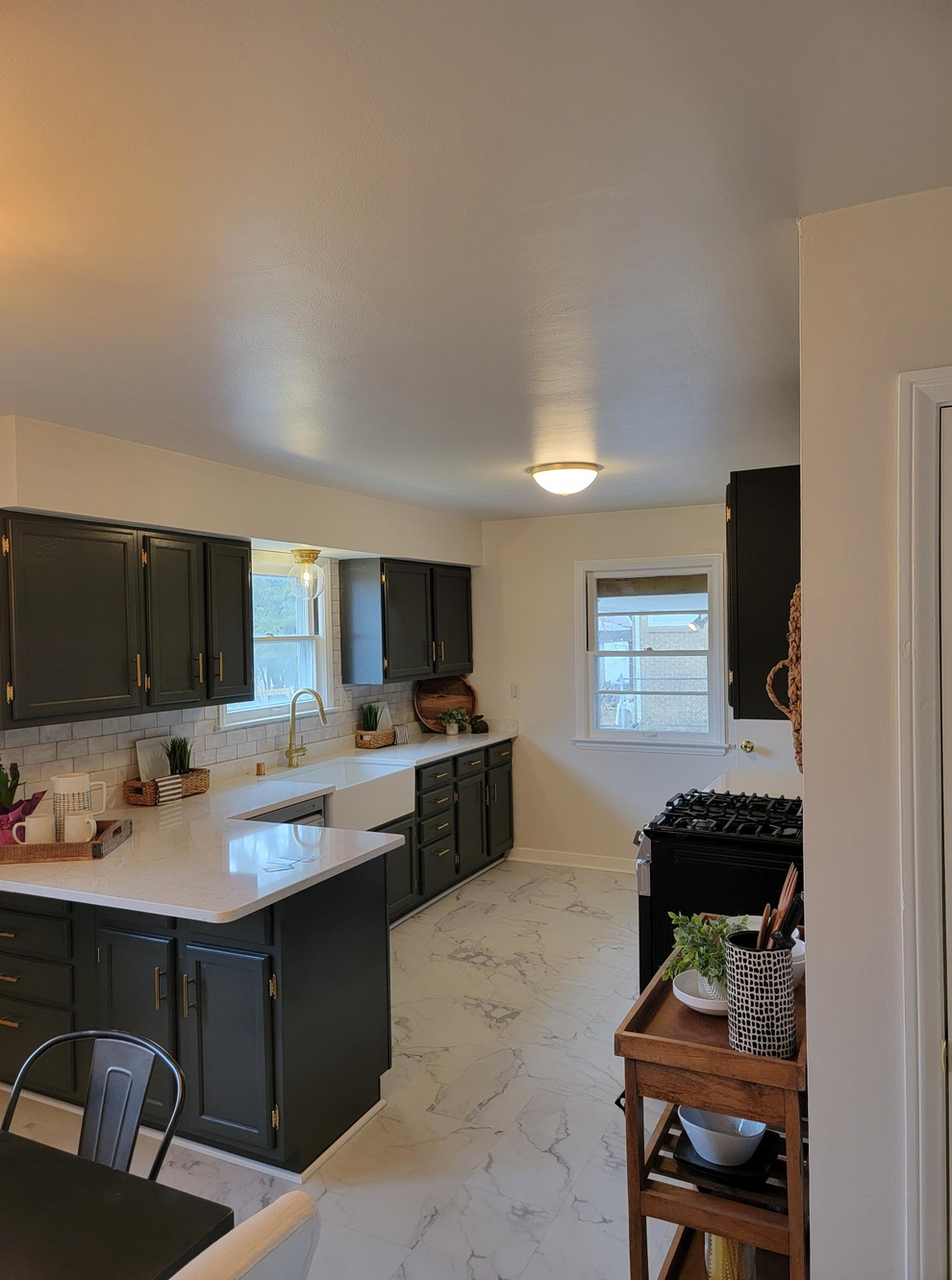 Modern kitchen with dark cabinets, white countertops, and a small window over a sink